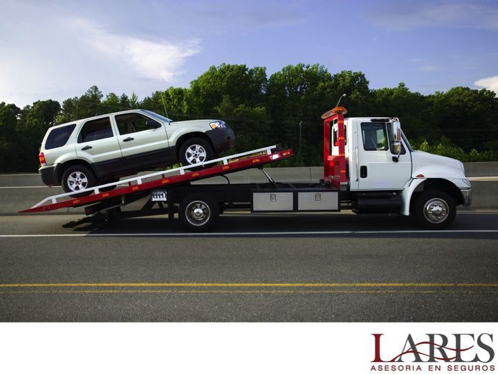 Grúa cama trasladando un SUV por la carretera